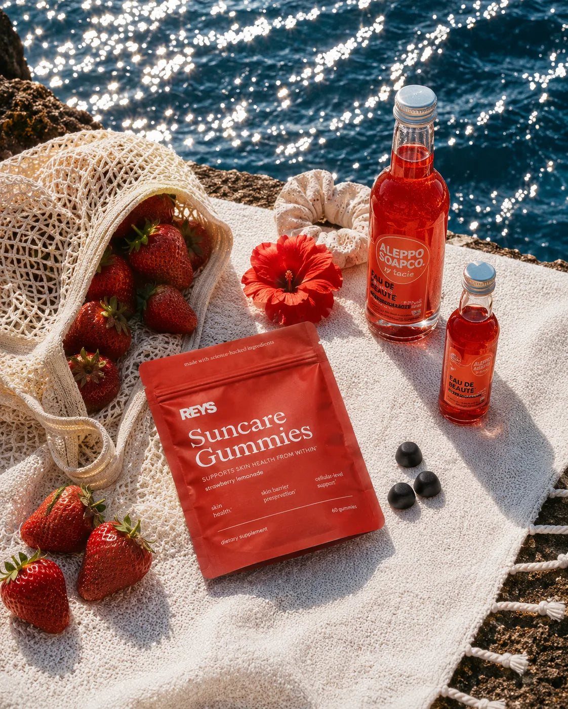 REYS Suncare Gummies pouch with fresh strawberries by the sea